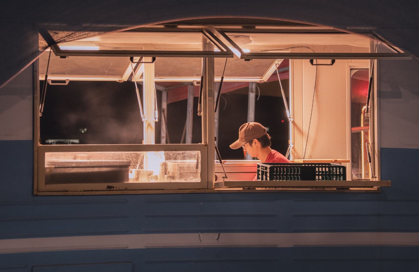 Cocinero trabajando dentro de un food truck por la noche